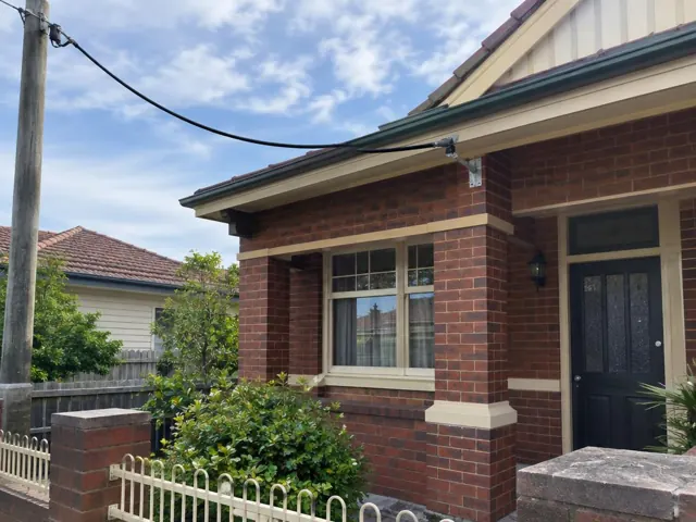 Brick house facade with overhead service cable and new fascia bracket in Teralba